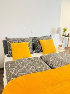 a bed with yellow and gray sheets and pillows at Apartment in Zentrumsnähe NETFLIX SELF CHECK-IN in Augsburg