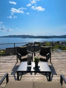 a patio with two chairs and a table with a view of the water at 2 leiligheter med panoramautsikt in Bergen