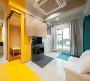 - un salon avec un canapé blanc et un mur jaune dans l'établissement BOB Hostel सुख सदन ひだまり庵 파란달여관, à Bangkok