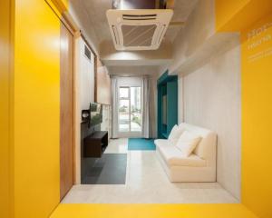 - un salon avec un canapé blanc et un mur jaune dans l'établissement BOB Hostel सुख सदन ひだまり庵 파란달여관, à Bangkok