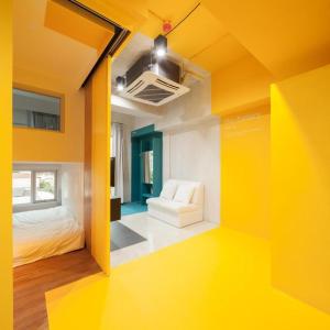 Cette chambre jaune comprend un lit et une chaise. dans l'établissement BOB Hostel सुख सदन ひだまり庵 파란달여관, à Bangkok