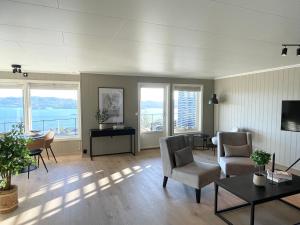 a living room with chairs and a table and windows at 2 leiligheter med panoramautsikt in Bergen