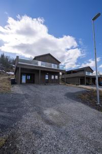 a house on a gravel road in front of a building at Steam Apartments - Eidhøgda 6 in Tromsø