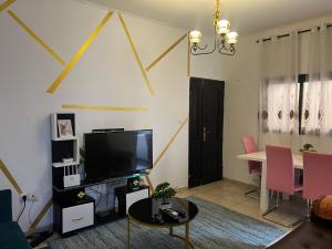 ドゥアラにあるServices Meubléのテレビとテーブル、ピンクの椅子のあるリビングルーム