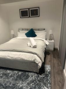 a bedroom with a bed with white sheets and blue pillows at HE Luxury in Abbey Wood