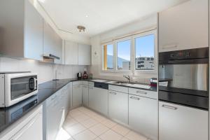 a kitchen with white cabinets and black appliances at Casa Verbanella - Objekt 7500 in Minusio +14 photos