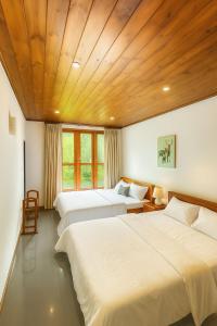 a bedroom with three beds and a wooden ceiling at Sweet Villa Hotel in Peradeniya