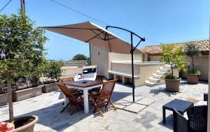 a patio with a table and chairs and an umbrella at Casa Badia in Santa Venerina