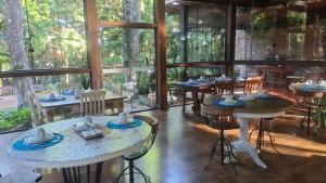 a dining room with tables and chairs and windows at Bosque São Francisco in Chapada dos Guimarães