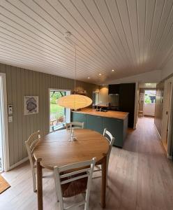 a dining room and kitchen with a wooden table and chairs at Cozy 6 person holiday home in Juelsminde - 5 minutes walk to the beach in Sønderby