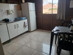 a kitchen with a table and a white refrigerator at Casa das Embaúbas 05 in São José