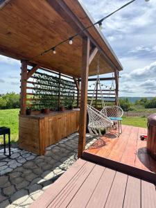 a wooden pergola with a hammock on a patio at Cabana Refugio in Bălceşti