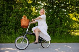 a woman in a dress riding a bike with a dog in a basket at Kuća za odmor Mia in Stankovac