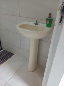 a white sink in a bathroom with a green cup at Casa das Embaúbas 05 in São José +2 photos