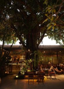 a group of people sitting at tables under a tree at Villa KHAYA Seminyak Stylish 2-Bedroom Villa Just 900m from the Beach in Badung