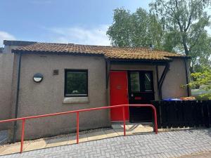 una piccola casa con una porta rossa e una ringhiera rossa di Two bedroom cottage in Lumsden - Contractors a Huntly