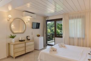 a bedroom with a white bed and a mirror at Villa Romantica Hotel in Paleo Tsifliki