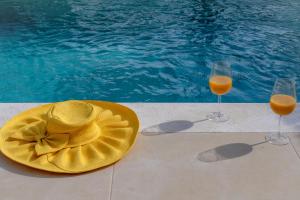 einen Hut und zwei Gläser Orangensaft neben einem Pool in der Unterkunft Anna Luxury Villas by RentalsPro - Nea Flogita Halkidiki in Flogita