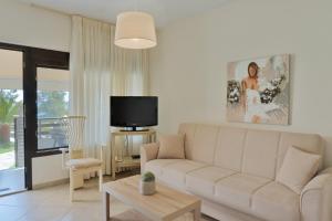 a living room with a white couch and a tv at Villa Romantica Hotel in Paleo Tsifliki