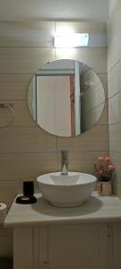 un bagno con un lavandino bianco e uno specchio di On The Rocks a Qeparo