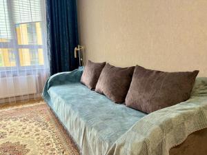 Un sofá azul en una habitación con ventana. en Modern apartment in the city center with 3 rooms studio, en Almaty