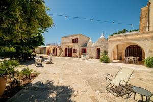Un patio de un edificio con sillas y mesas. en Masseria Trulli Bruni, en Locorotondo