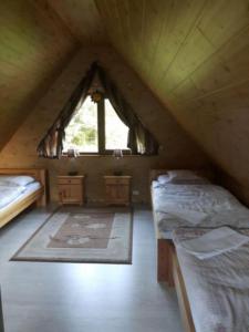 a attic room with two beds and a window at Domki z bali Polanica-Zdrój in Polanica-Zdrój