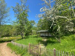 una valla junto a una casa en un campo en Tente Lodge en pleine nature, en Cros