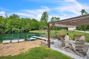 a patio with chairs and a boat on a lake at Lakeside Retreat with Hot Tub & Game Room home in Elkhart