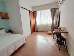 a bedroom with a bed and a table and a window at Good Stay in Tainan