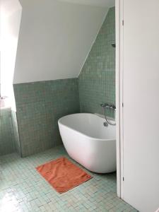 a white tub in a bathroom with green tiles at Beautiful flat, 30 min away from central London in Bromley