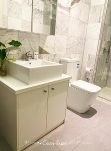 a white bathroom with a sink and a toilet at Cozy Suite in Clayton North