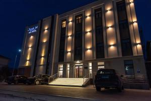 a building with two cars parked in front of it at Jipek joli ART in Nukus