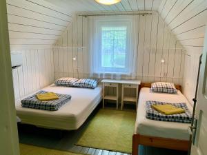 two beds in a small room with a window at Maple House - Sodyba Tarp Klevų in Utena