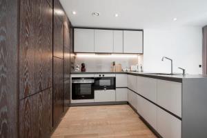 a kitchen with white cabinets and wooden walls at Modern 2 Bed Battersea Power Station in London +29 photos