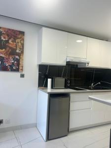 a kitchen with white cabinets and a microwave at Studio jardin cap d Agde in Cap d'Agde