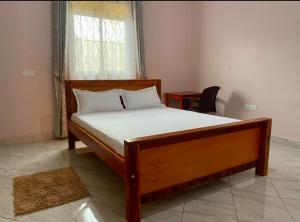 a bedroom with a wooden bed with a window at Pearl Season B&B in Gulu