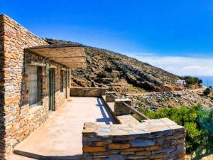 a stone house on a hill with the ocean in the background at La Priva Calma in Agios Ioannis