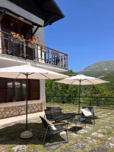 two chairs and two umbrellas in front of a building at L'Orsa in Villalago