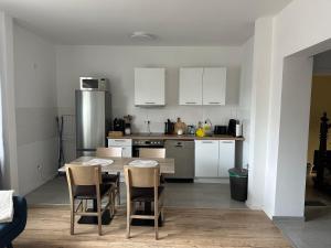 a kitchen with white cabinets and a table and chairs at Appartment Zur Blume in Bremerhaven
