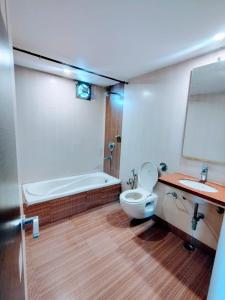 a bathroom with a tub and a toilet and a sink at Hotel Apex Intercontinental in Jaipur