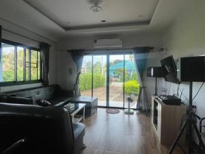 a living room with a couch and a tv at บ้านกลางนาพูลวิลล่า น่าน in Nan