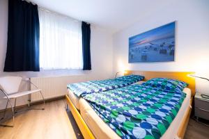 a bedroom with a bed and a chair and a window at Haus Albatros in Timmendorfer Strand