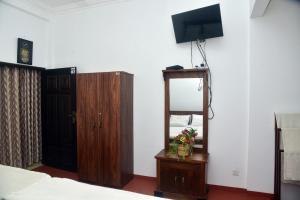 1 dormitorio con cama, espejo y TV en White House Resort, en Balangoda
