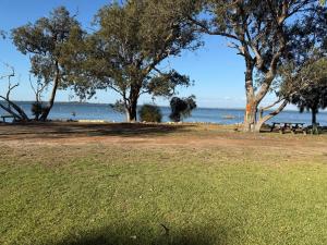 a park with trees and the ocean in the background at Waters Edge Retreat in Dawesville