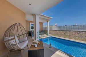 a villa with a swimming pool and a chair at Bela Vista Exclusive Private Villa in Praia da Luz in Luz