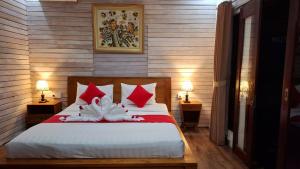 a bedroom with a bed with red and white pillows at Oka Cottage in Nusa Penida