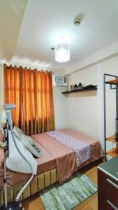 a bedroom with a bed with orange curtains at 3rd - Sea View of Seawind Condominium in Davao City +34 photos