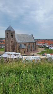 an old church with a clock tower in front of it at Dulce Tierra - appartement in Zoutelande
