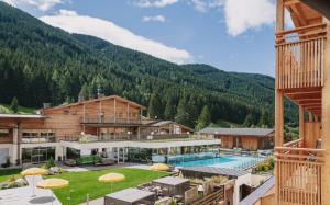 Ein Resort mit Pool und Bergen im Hintergrund in der Unterkunft Alpine Nature Hotel Stoll in Gsieser Tal